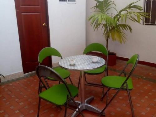 einen Tisch und vier grüne Stühle und eine Pflanze in der Unterkunft HOTEL CASA GARCES in Cartagena de Indias