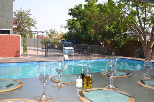 Windhoek Gardens Boutique Hotel في ويندهوك: طاولة مع كؤوس للنبيذ أمام حمام السباحة