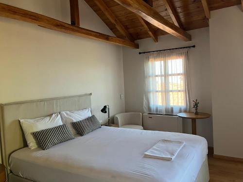 una camera da letto con un grande letto bianco e una finestra di Melofegaro Guesthouse a Palaios Panteleimon