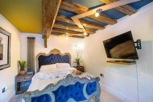 a bedroom with a blue bed and a flat screen tv at King Suite In 600 Year Old Manor House In Saffron Walden North Essex in Saffron Walden