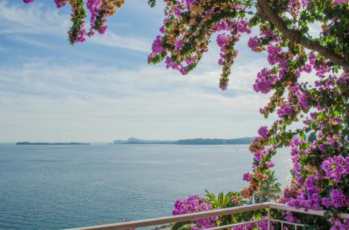 a view of the water and flowers at Hotel Villa Florida & Suite Apartments in Gardone Riviera