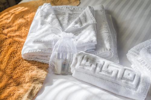 a pile of towels and a bottle on a bed at Deluxe 2 Bed Versace Bungalow Hot Tub, Sky TV, Cinema Screen Saffron Walden in Saffron Walden