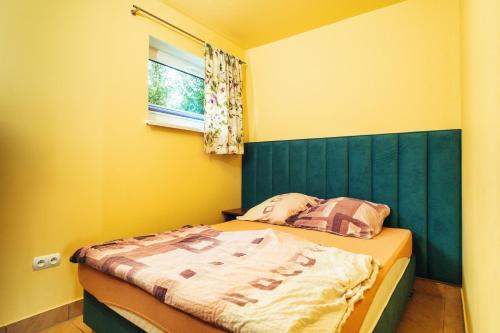 a small bedroom with a bed with a green headboard at Całoroczne Domki w Bieszczadach "The Willows" in Łączki