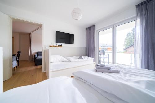 a white bedroom with two beds and a window at Apartment 104 in Feldberg
