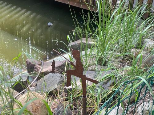 a metal statue in the grass next to a pond at Harzhotel Warnstedter Krug in Thale