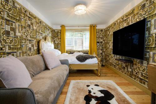 a living room with a couch and a flat screen tv at Deluxe 2 Bed Versace Bungalow Hot Tub, Sky TV, Cinema Screen Saffron Walden in Saffron Walden