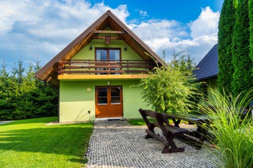 a green house with a bench in front of it at Całoroczne Domki w Bieszczadach "The Willows" in Łączki