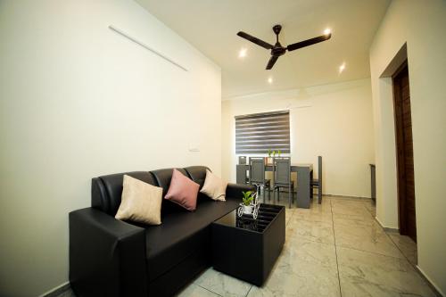 a living room with a black couch and a ceiling fan at Shams al Imarat in Palakkad