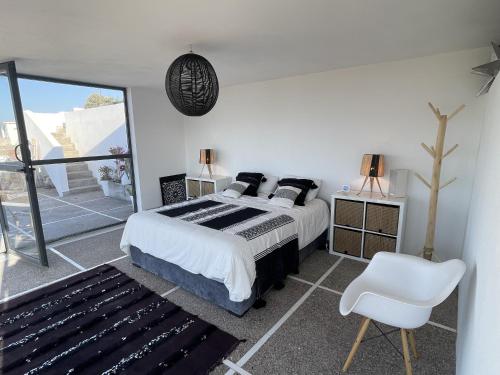 a bedroom with a large bed and a white chair at Dar Bouba, Cap Sim : la maison sur l'Océan in Wassane