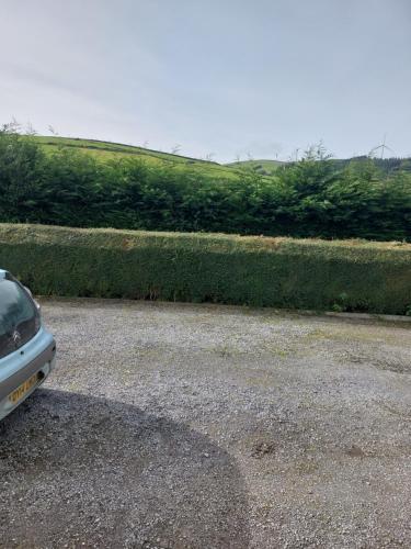 ein Auto, das auf einem Parkplatz neben einer Hecke parkt in der Unterkunft Hillside Haven in Tipperary