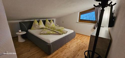 Un dormitorio con una cama con almohadas amarillas y una ventana en Ferienwohnung Schranz en Flirsch