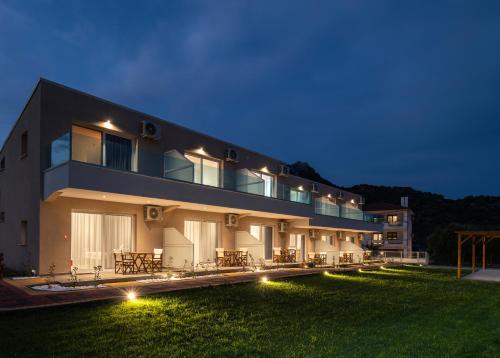 a large building with lights on the grass at night at Diva Lodge in Sikia