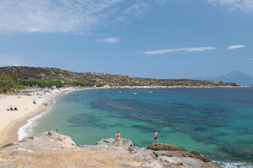 a group of people standing on rocks on a beach at Diva Lodge in Sikia