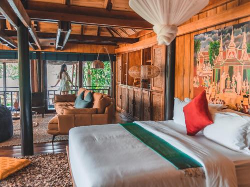 a bedroom with a large bed and a living room at Devi Kampot Resort at Phum Kampot in Kampot