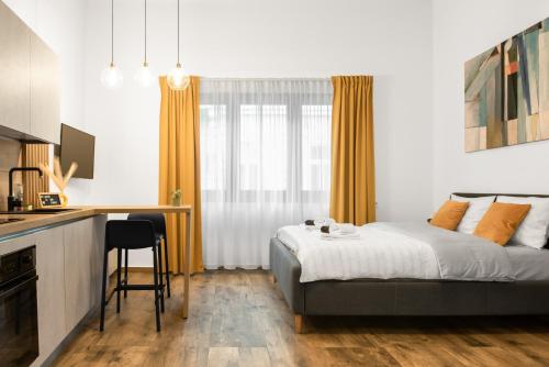 a bedroom with a bed and a desk and a kitchen at Studio in the heart of Cluj in Cluj-Napoca