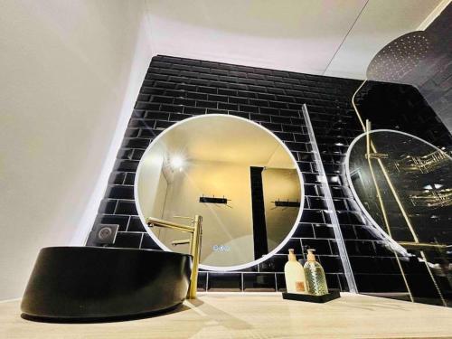 a bathroom with a round mirror on a black brick wall at L'Héliodore, Apt 4 Prs Standing, Clim, Parking in Antibes