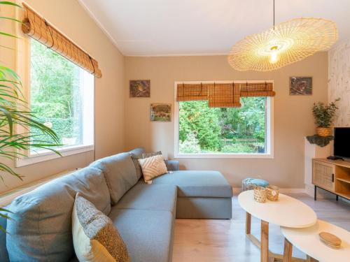 a living room with a blue couch and two windows at Holiday Home in Gelderland near Woodlands in Hattemerbroek
