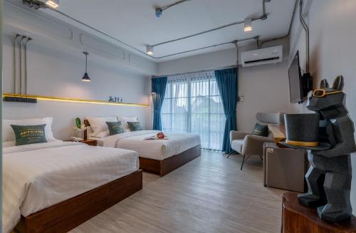 a hotel room with two beds and a tv at Momo Hotel in Chiang Mai