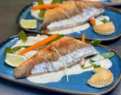 two plates of food with fish and vegetables on them at LOGIS HÔTEL, CHALETS et RESTAURANT LES CHATELMINÉS in La Bresse
