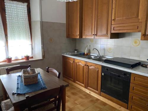 - une cuisine avec des placards en bois, une table et un évier dans l'établissement intero appartamento, à Ponte dʼArbia