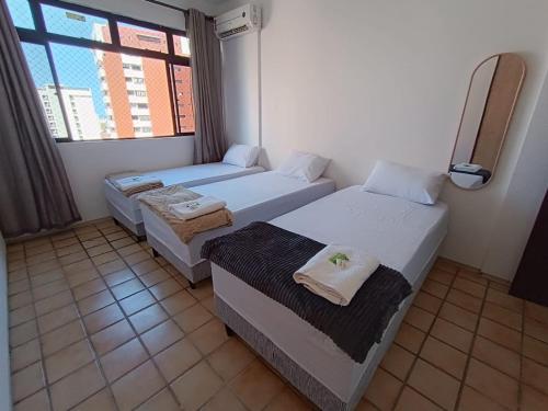 a small room with two beds and a window at HostellHouse Márcia Guimarães in João Pessoa