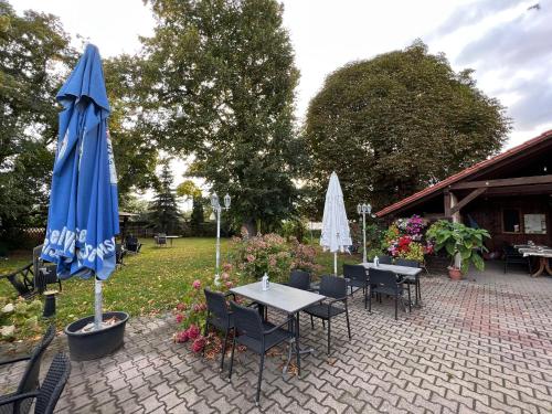un patio avec des tables et des parasols dans un jardin dans l'établissement Gasthaus Kelly, à Magdebourg