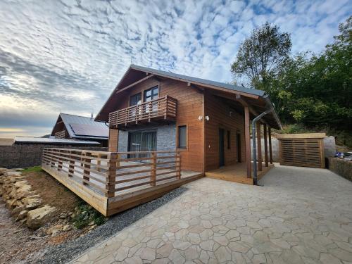 ein Holzhaus mit einer Veranda und einem Balkon in der Unterkunft Chalet Fiona with jacuzzi in Mýto pod Ďumbierom