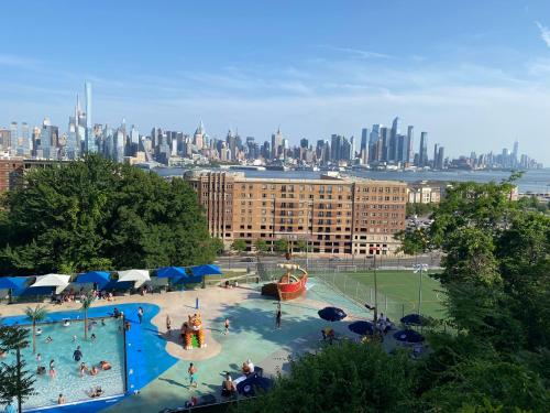 a large swimming pool with a city in the background at Lovely Cozy apt West NY NJ Excellent transportation 12 minutes to NY 7 minutes at NYWater Way Ferry in West New York