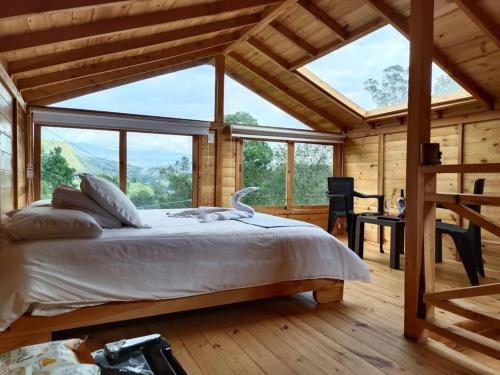 a bedroom with a large bed with a large window at Ecocabaña con Jacuzzi Ecocabañas ByB in Choachí