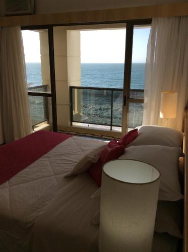 1 dormitorio con cama y vistas al océano en Lexus Beira Mar - Apartamentos, en Florianópolis
