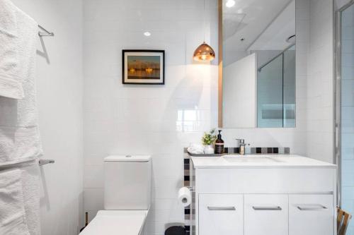 a white bathroom with a sink and a mirror at Modern, Spacious 2BR Penthouse with Bay Views in Geelong