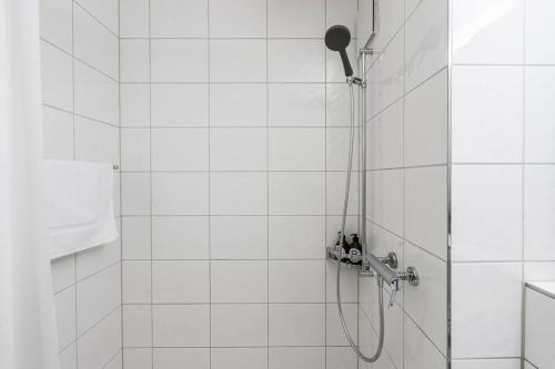 a white bathroom with a shower with a shower head at Bright & Central Studio Home Office & Netflix in Zurich