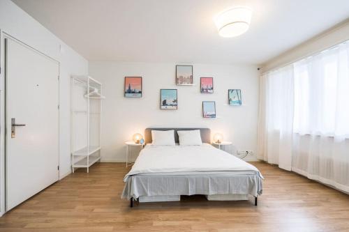a white bedroom with a bed and two lamps at Bright & Central Studio Home Office & Netflix in Zurich
