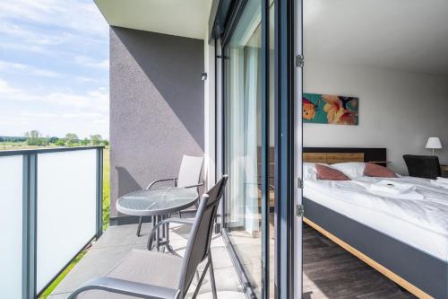 a bedroom with a bed and a balcony with a table and chairs at RELAX PARK Třeboň II in Třeboň