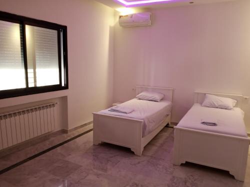 two beds in a small room with a window at DarNejib, Cité El Wafa Hammamet Nord in Nabeul
