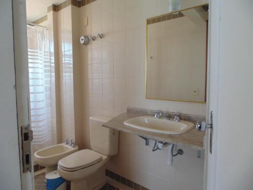 y baño con aseo, lavabo y espejo. en Lexus Beira Mar - Apartamentos, en Florianópolis