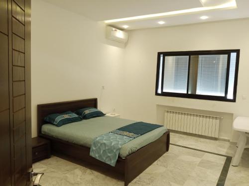 a bedroom with a bed and a window and a sink at Dar Nejib Apparts S1 S2 S3 et villa S4 in Nabeul