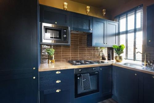 a kitchen with navy blue cabinets and a microwave at Luxury Versace Sleeps10 HotTub Pool Table SkyTV in London