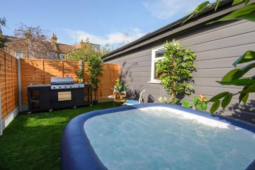 a backyard with a swimming pool and a barbecue at Luxury Versace Sleeps10 HotTub Pool Table SkyTV in London