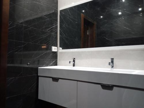 een badkamer met een witte wastafel en een spiegel bij Dar Nejib Apparts S1 S2 S3 et villa S4 in Nabeul