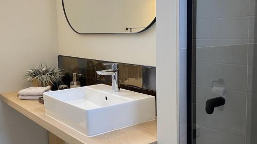 La salle de bains est pourvue d'un lavabo blanc et d'un miroir. dans l'établissement bij DE RODE DEUR, à Meppel