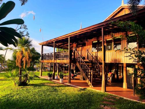a large wooden building with a staircase on it at Devi Kampot Resort at Phum Kampot in Kampot