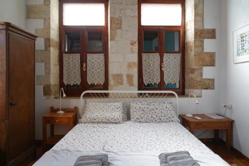 um quarto com uma cama com duas mesas e duas janelas em Lindas Convent Garden Home 4 em Chania