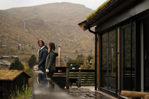 un hombre y una mujer parados en el balcón de una casa en Unique Romantic Cabin with Mountain View at Strandafjellet, Mivo X, en Stranda