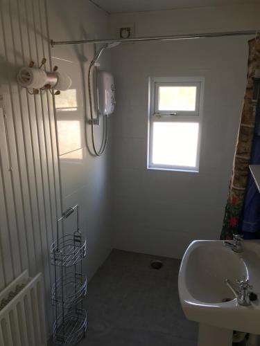 a white bathroom with a sink and a window at Brigid M’s Farm House in Killashandra