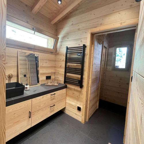 - une salle de bains en rondins avec lavabo et miroir dans l'établissement Chalet Skidh - 10 personnes - emplacement idéal au centre de Vaujany, à Vaujany