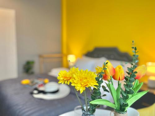 a vase filled with yellow and orange flowers on a table at Studio room in Mango House in Phuket Town