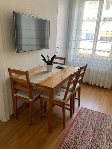 mesa de madera con 2 sillas y TV en la pared en 2 Zimmer Appartement, en Winterthur