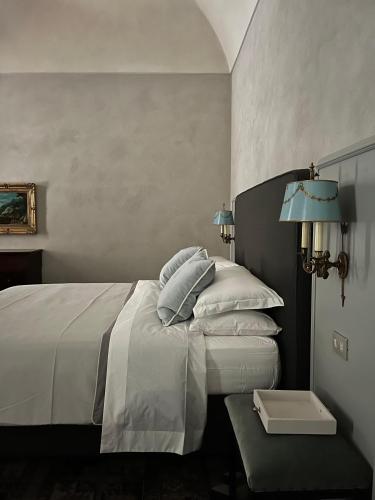 een slaapkamer met een bed met witte lakens en blauwe lampen bij Suite Vittorio Emanuele in Alba