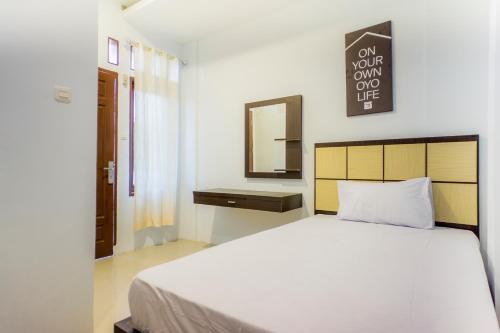 a bedroom with a large white bed and a mirror at OYO Life 2354 Rose House in Medan